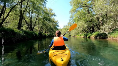 Kayaking Serene River - A kayaker paddles down a calm river, surrounded by lush green trees and vegetation. The tranquil scene showcases the beauty of nature and peaceful outdoor activities.