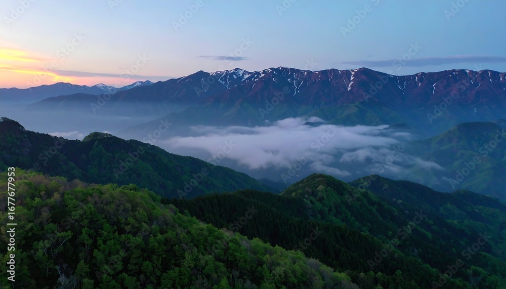Fototapeta premium A breathtaking vista of mountain ranges bathed in the soft hues of dawn, with layers of misty clouds cascading through valleys.