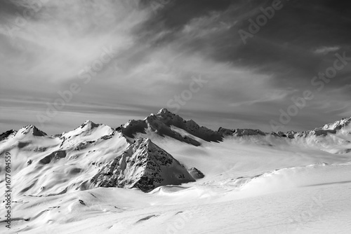 Black and white view on off-piste slope at sun evening
