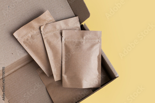 Kraft brown paper empty bags isolated mock up on yellow background. Eco friendly pack with zipper, roasted specialty coffee beans, tea, snack, alternative sample trendy concept. top view, flat lay