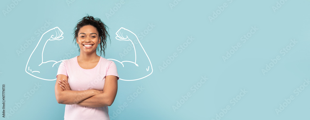 Naklejka premium A confident African American woman stands with crossed arms, smiling against a blue background. Illustrations of strong biceps are drawn behind her, symbolizing strength and resilience.