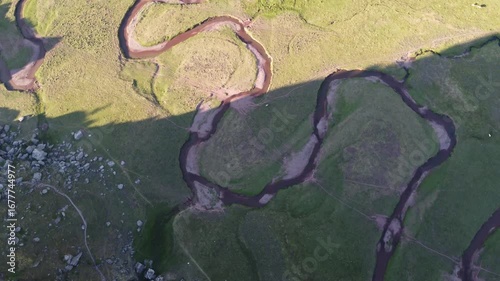 top aerial view of a sinuous river meander in a green field