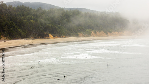 Surfers and paddle boarders ride the gentle waves along Oregon’s foggy coast near Newport Beach.