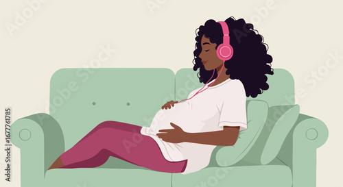 Dark-skinned pregnant woman relaxes to music, listening to music with pink headphones, on soft sofa.