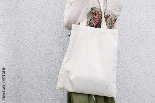 Young white woman holding black eco bag on arm shoulder or hand, street wall at background. city living female going on shopping to grocery store