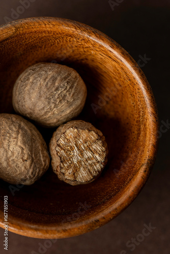 Closeup of whole nutmeg in a small wood bowl 