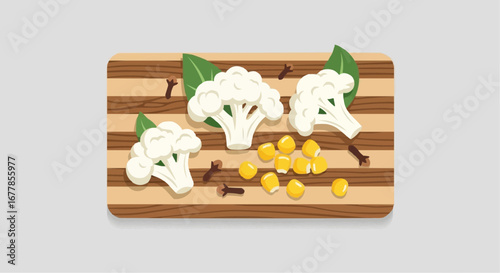Fresh cauliflower florets arranged with corn kernels and cloves on a wooden cutting board with green leaves.