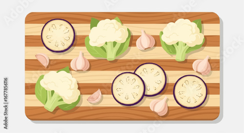 Overhead view of a wooden cutting board with fresh cauliflower, eggplant slices, and garlic cloves.