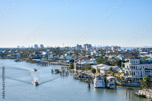 Boats cruising by waterfront homes in Fort Myers Beach on Estero Island, southwest Florida in Lee County