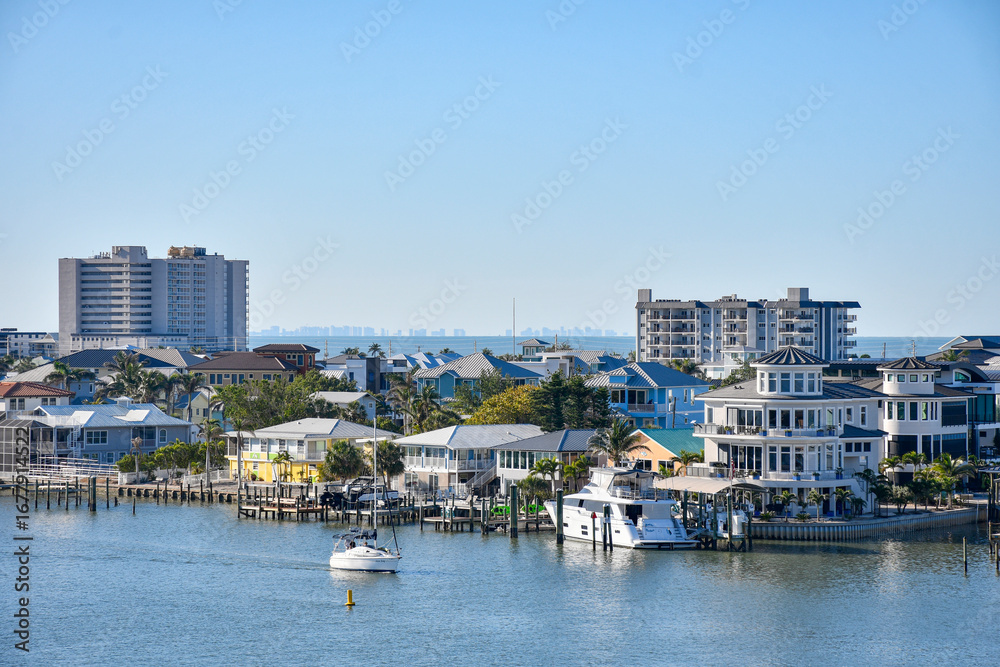 Obraz premium Sailboat passing by waterfront homes in Fort Myers Beach on Estero Island, southwest Florida in Lee County