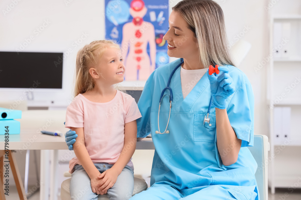 Fototapeta premium Female endocrinologist with thyroid gland model and little girl in clinic