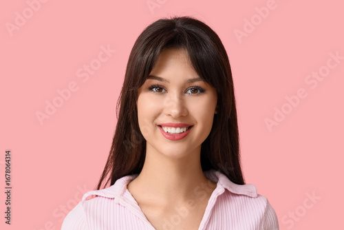 Smiling young woman on pink...