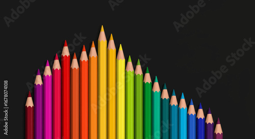 Rainbow array of colored pencils against black arranged by height forming a peak