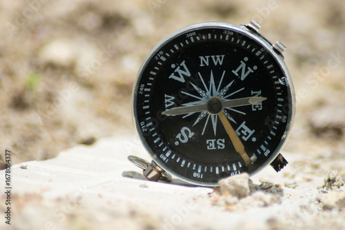 Vintage compass on sand in desert landscape, symbol of travel and exploration