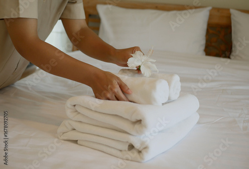 Bild auf Leinwand A housekeeper's hand is holding a white flower and placing it on a towel, prepar