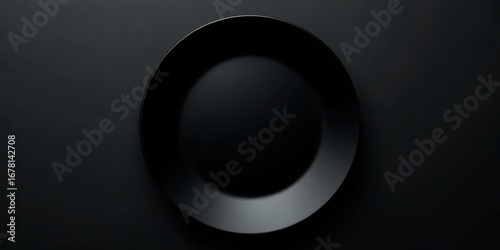 A solitary, matte black plate rests on a dark surface, a minimalist image perfect for culinary or design projects.