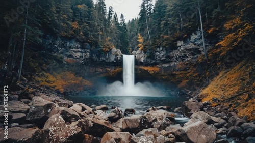 Majestic waterfall cascades powerfully into serene blue water amidst lush forest