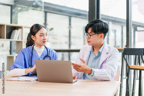 Fotografía Young medical professionals discussing patient case at laptop, focused and colla