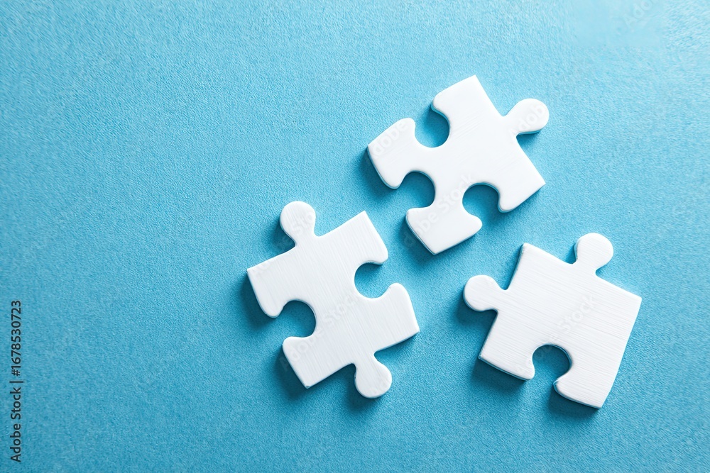 Obraz premium Three white jigsaw puzzle pieces on a light blue background