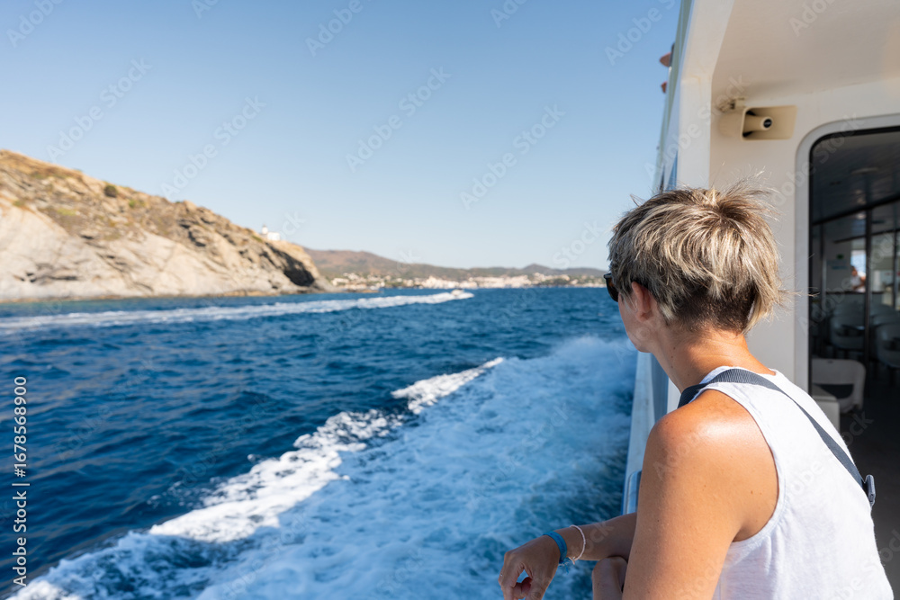 Fototapeta premium Tourist enjoying the view of the mediterranean sea and the rocky coast from boat trip near cadaques
