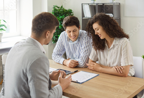 Canvas Print Male financial advisor consulting young couple about insurance sitting at the desk in office