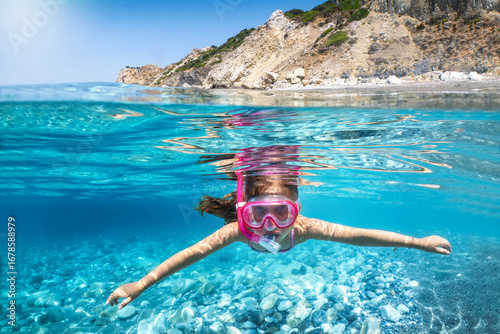 Canvas Print Underwater split view of a girl snorkeling in the turquoise, mediterranean sea d