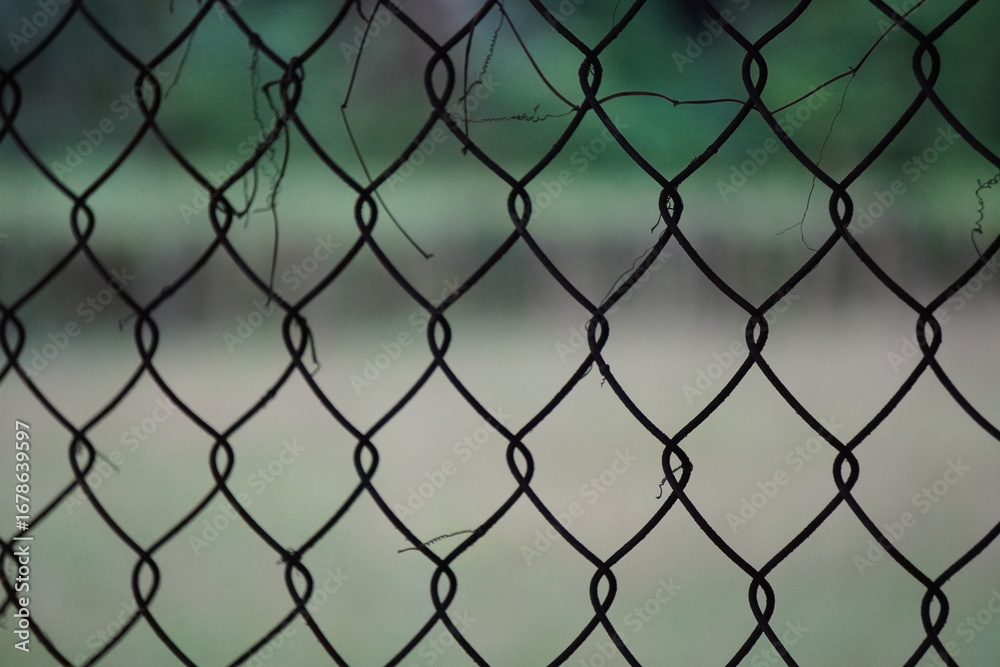 Naklejka premium Black Chain-Link Fence with Blurred Natural Background