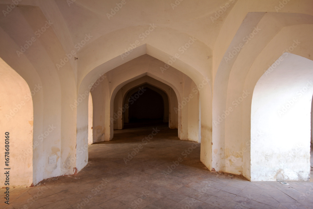 Fototapeta premium An interior view of a historic Indian fortress, featuring a repeating pattern of white-washed arched doorways, creating a sense of depth and symmetry. Ideal for travel guides and architectural history