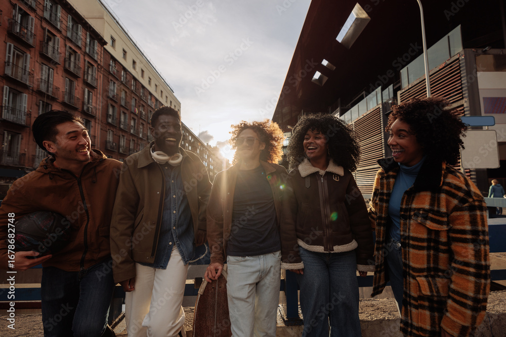 Obraz premium Happy multiracial friends walking together in the city at sunset