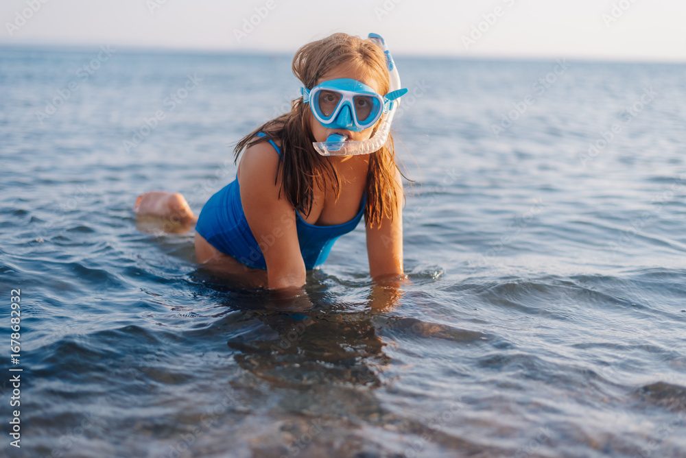 Naklejka premium Young girl wearing snorkel mask entering ocean for exciting summer adventure