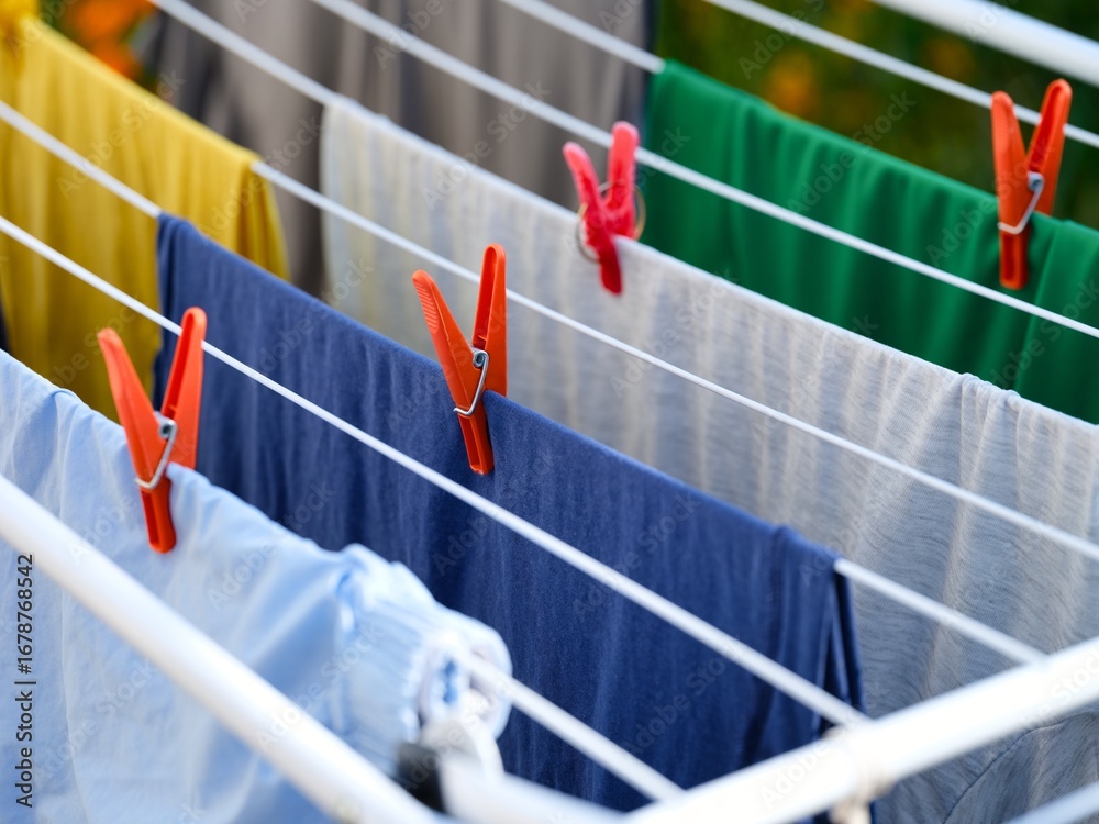 Naklejka premium Washed laundry hanging on a clothing dryer rack outdoors. Close-up.