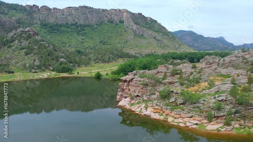 Rocky shores with pine trees reflecting in the calm lake water.