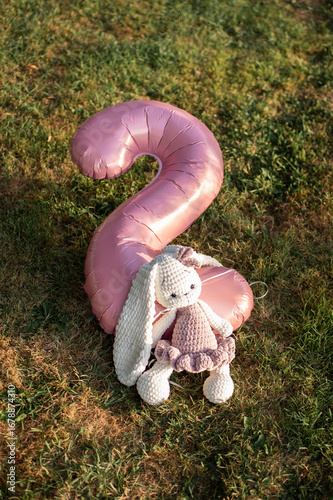 Vertical photo of a pink number 2 birthday balloon on autumn grass with a cute white-pink bunny nearby, perfect for fall birthday celebrations