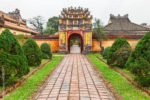 Ornate historic gate with tiled path and manicured garden in Hue Imperial City Vietnam