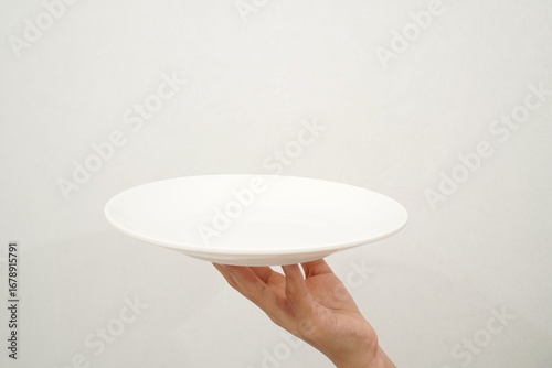 Woman's hand holding an empty plate isolated on white background