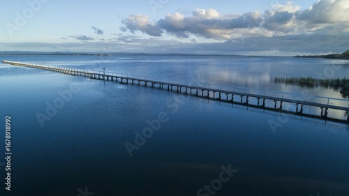 Wallpaper Mural Aerial view of the long jetty stretching far into the shimmering, dark blue waters under a serene sky, Lakes Entrance, Victoria, Australia. Torontodigital.ca