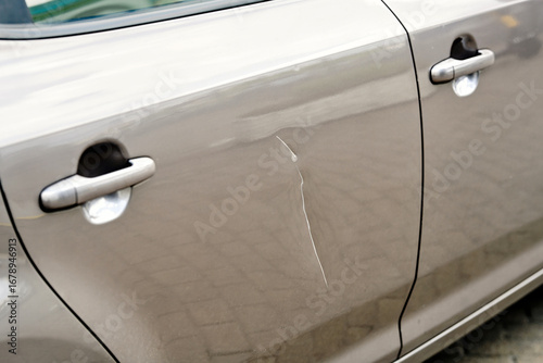Papier peint Damaged vehicle door with long deep paint scratch, visible dent, chipped coating
