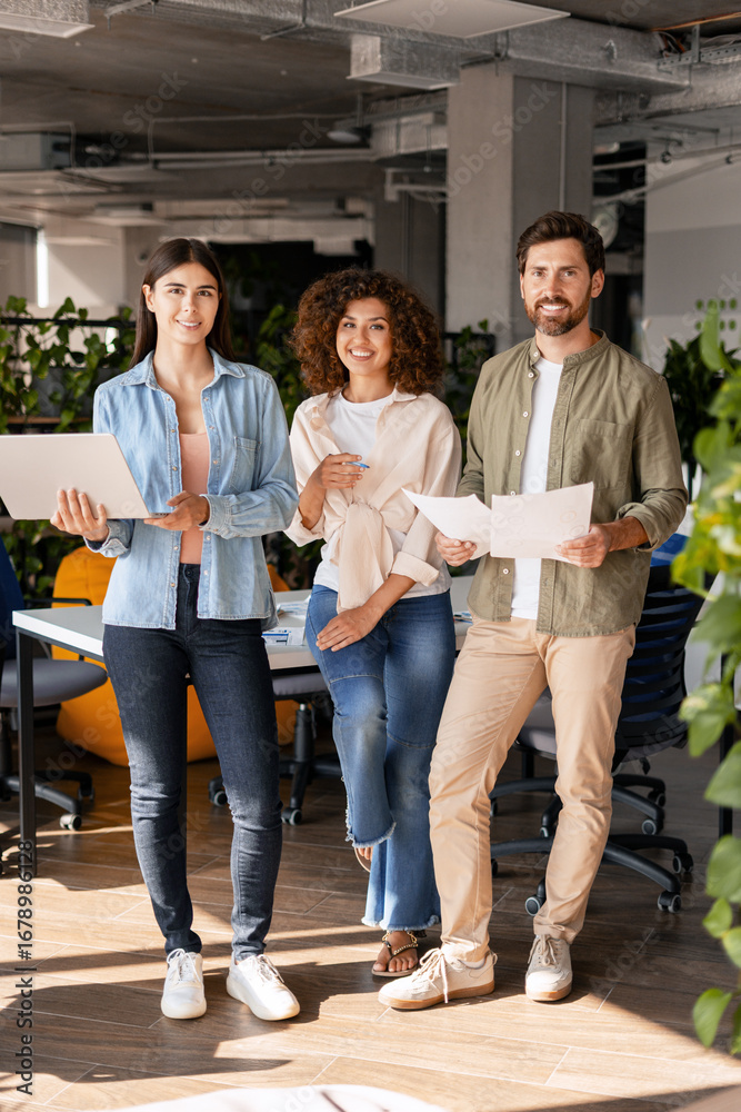 Fototapeta premium Startup team posing in modern office with documents and laptop