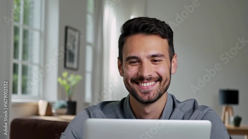 Smiling man working on laptop in bright living room 
