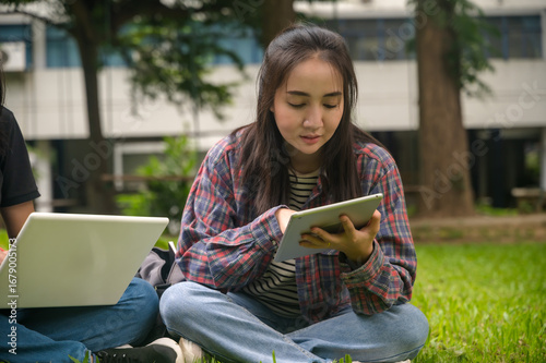 Young Asian female college student working with tablet in campus