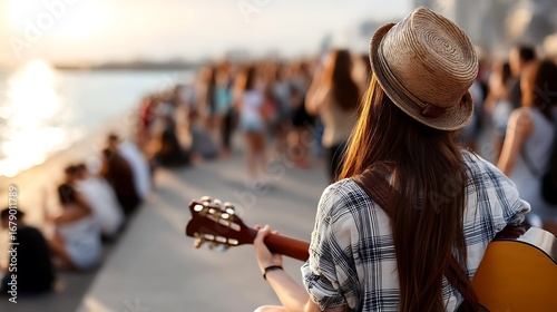 Country guitarist in cowboy hat performing at open air event by the beach during sunset