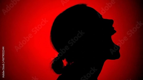 Silhouette of a woman's head in profile, mouth open, against a red background