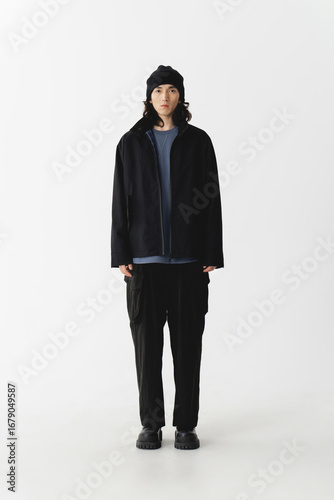 Papier peint Young man in casual black jacket and cargo pants standing in a minimalistic studio