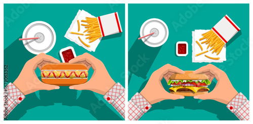 Hands holding a hot dog and hamburger, with soda, french fries and ketchup. Fast food and street food concept.
