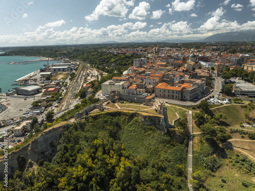 Aerial view of the vibrant harbor juxtaposed against the ancient Aragonese Castle ruins and lush greenery, Ortona, Abruzzo, Italy.