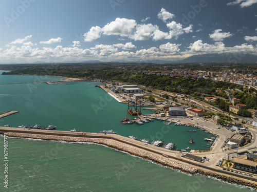 Wallpaper Mural Aerial view of the vibrant turquoise harbor embraced by Ortona's coastline, where industrial structures meet the azure sky, Ortona, Abruzzo, Italy. Torontodigital.ca