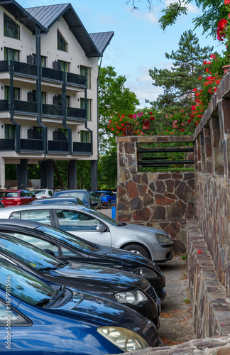 view of parking lot with cars and hotel decorated with flowers, concept of car travel and comfortable rest