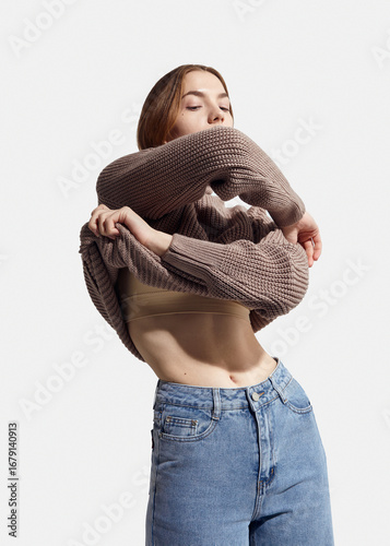 A beautiful woman takes off her beige autumn sweater