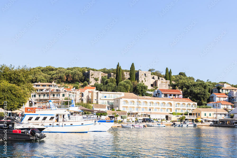 Stunning Kassiopi village on Corfu island featuring traditional Greek architecture, ancient fortress ruins, and fishing boats in the pristine Ionian Sea harbor. Stunning Kassiopi village on Corfu island featuring traditional Greek architecture, ancient fortress ruins, and fishing boats in the pristine Ionian Sea harbor.