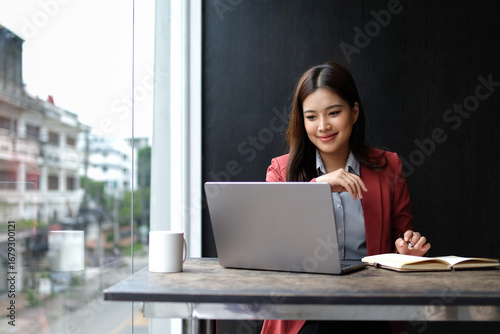 A businesswoman is working on a laptop in an office space.